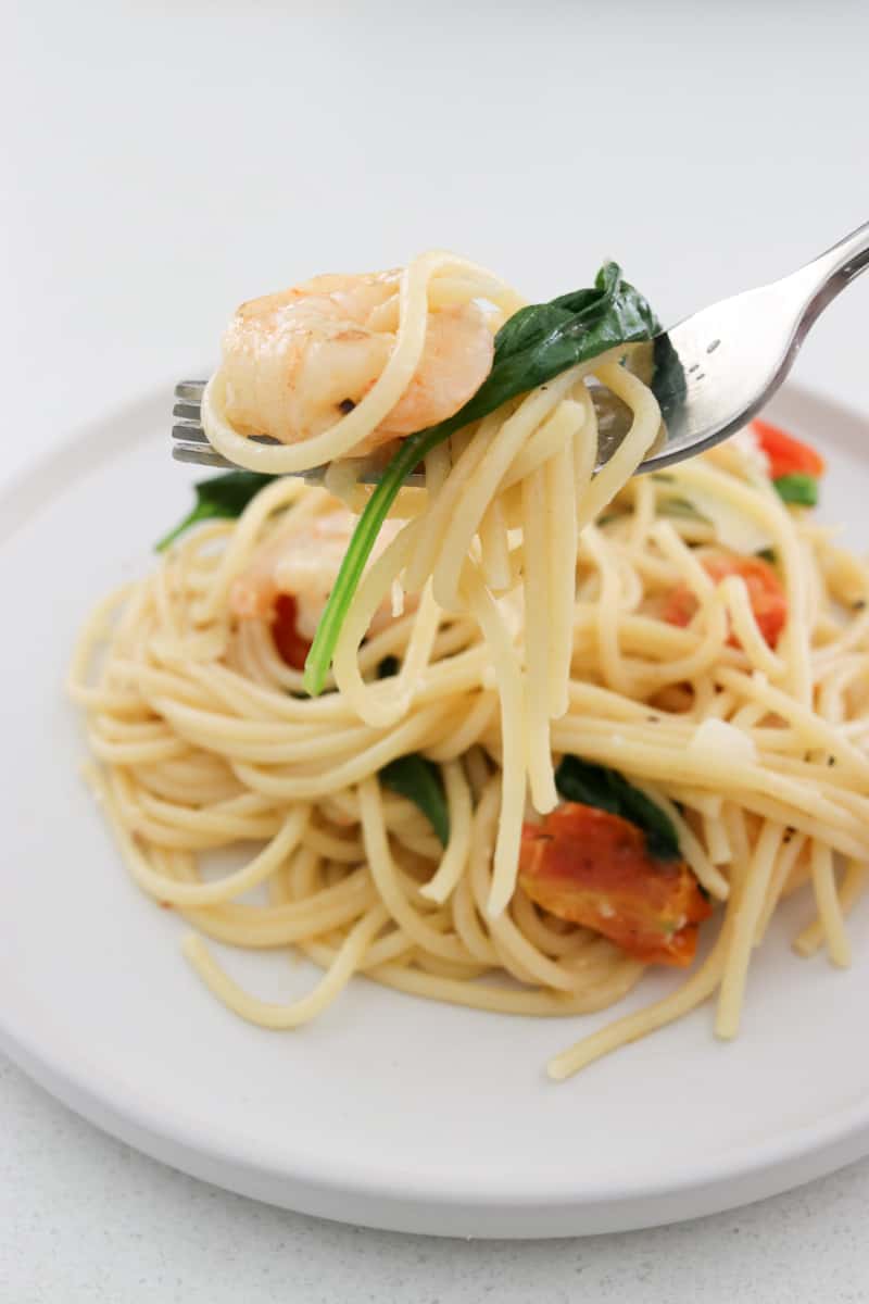 Prawn pasta with tomato and spinach on fork